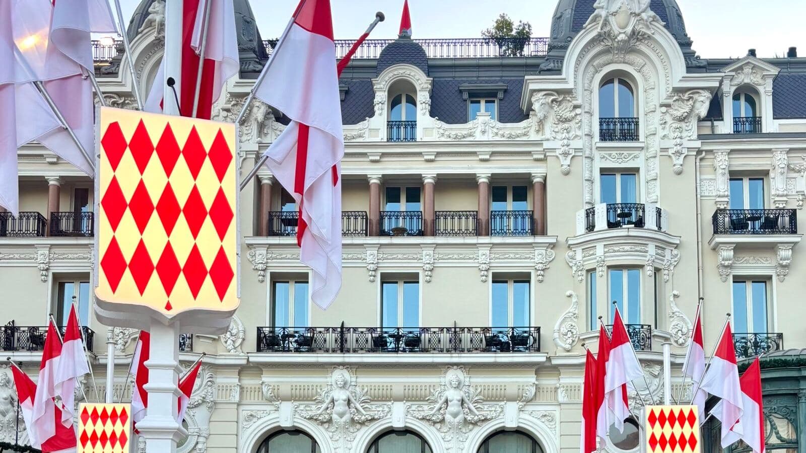The facade of the Hotel de Paris in Monte-Carlo decorated with Monaco's red and white flags.