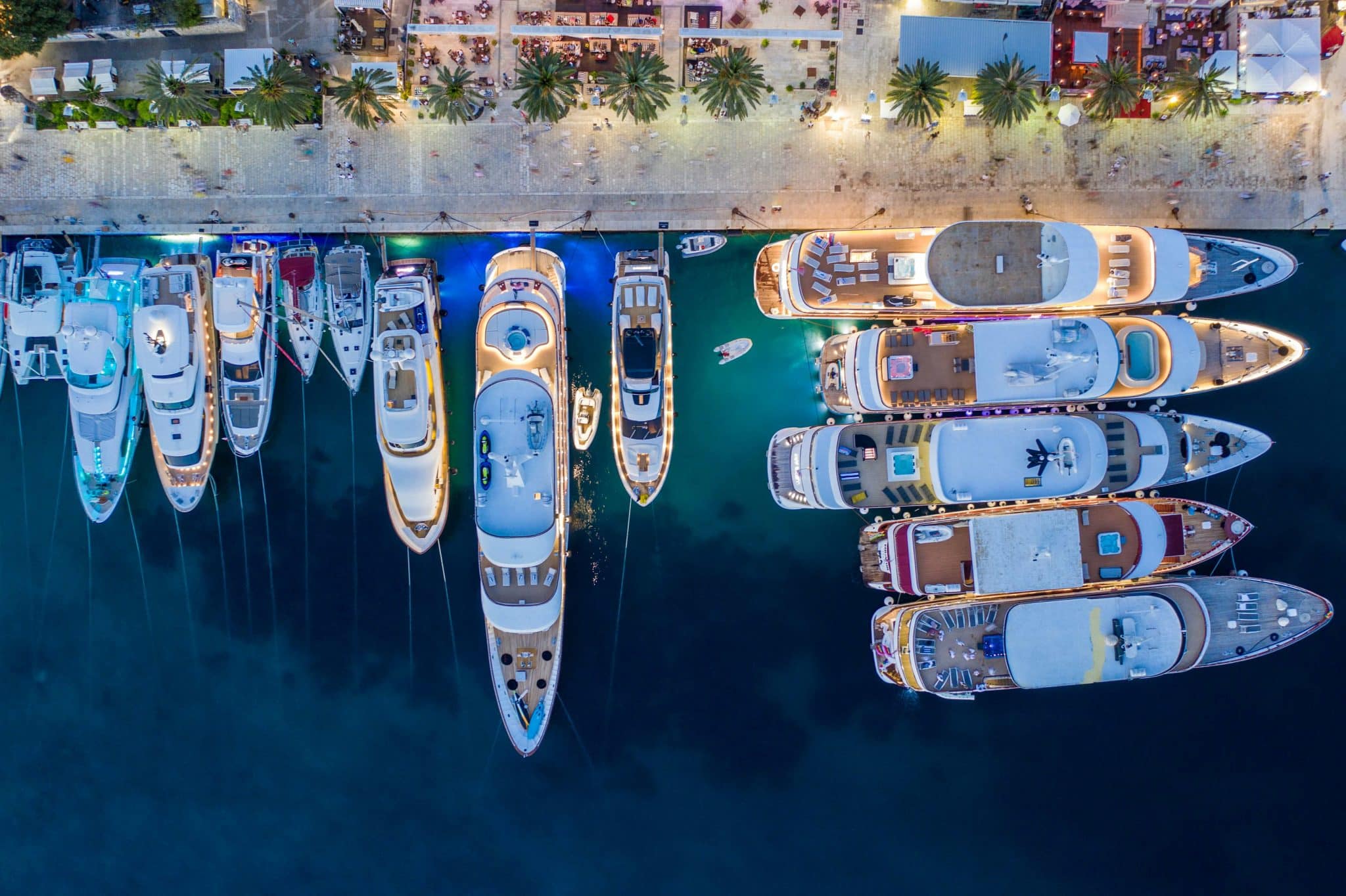 Vue aérienne de superyachts amarrés le long d'un quai illuminé la nuit