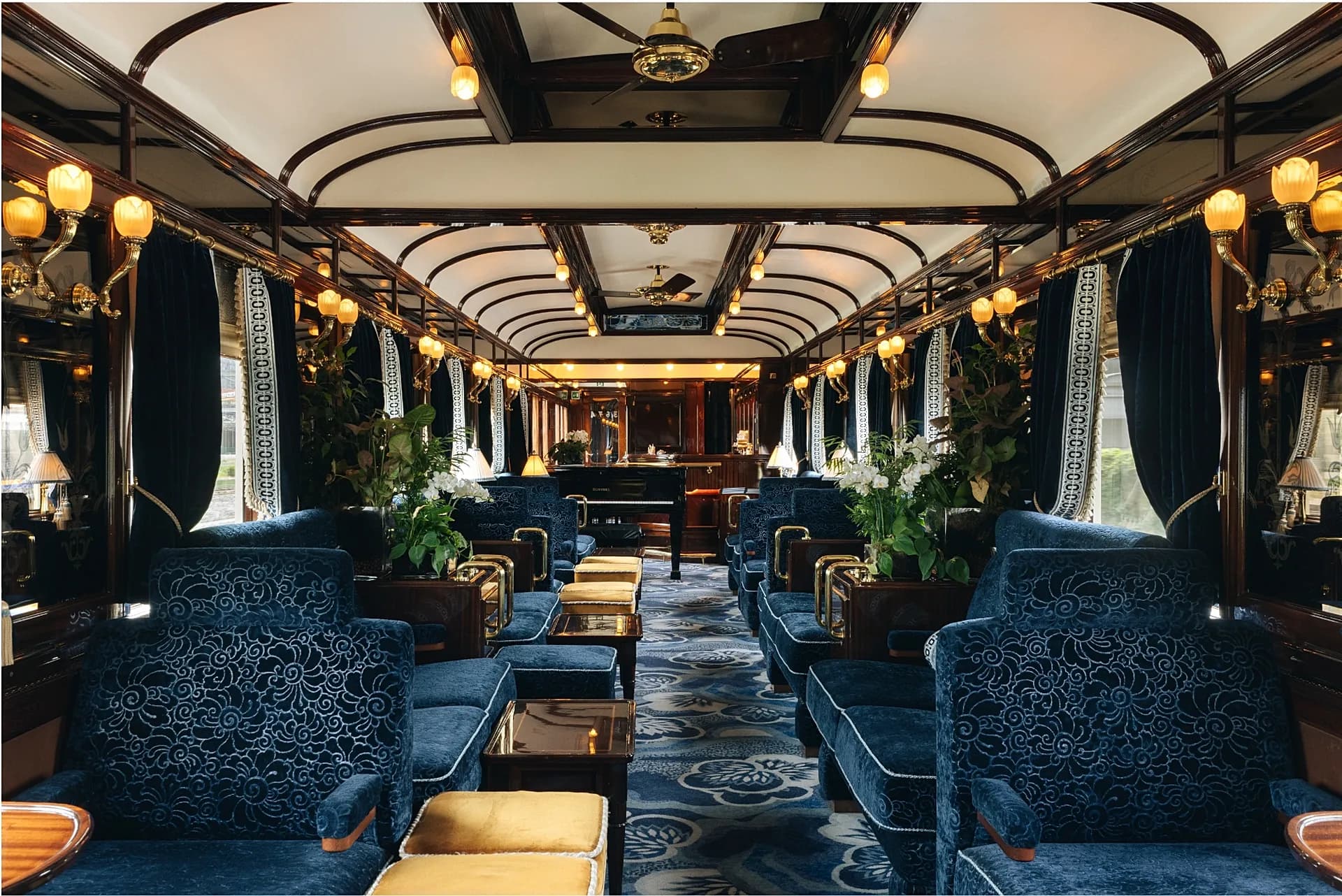 Intérieur du salon-bar du Venice Simplon-Orient-Express, avec fauteuils en velours bleu et piano
